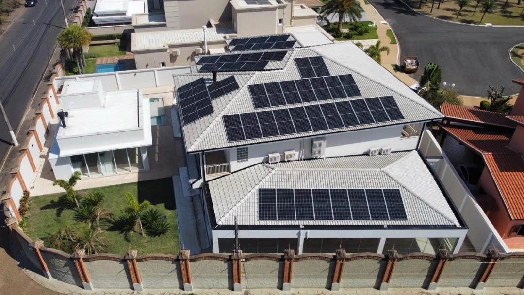 Sistema solar em telhado visto de drone com vias e estacionamentos ao redor